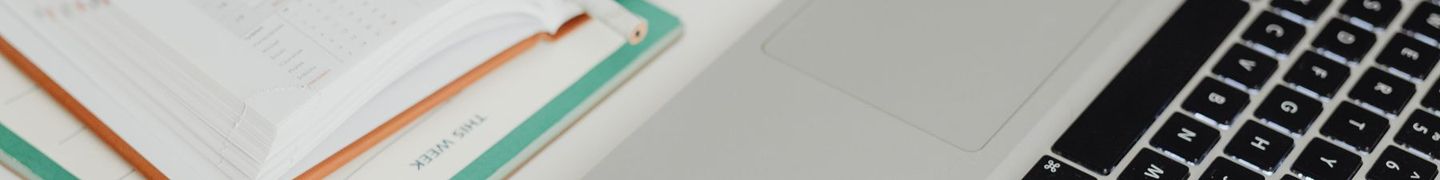 An open paper planner beside a laptop on a desk.